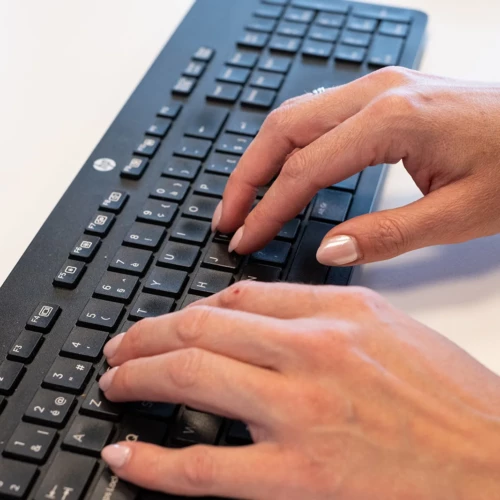 Close-up of hands typing on a computer keyboard.