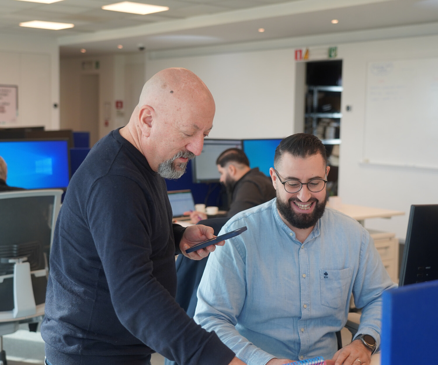 Two people coworking and smiling together in an office setting.