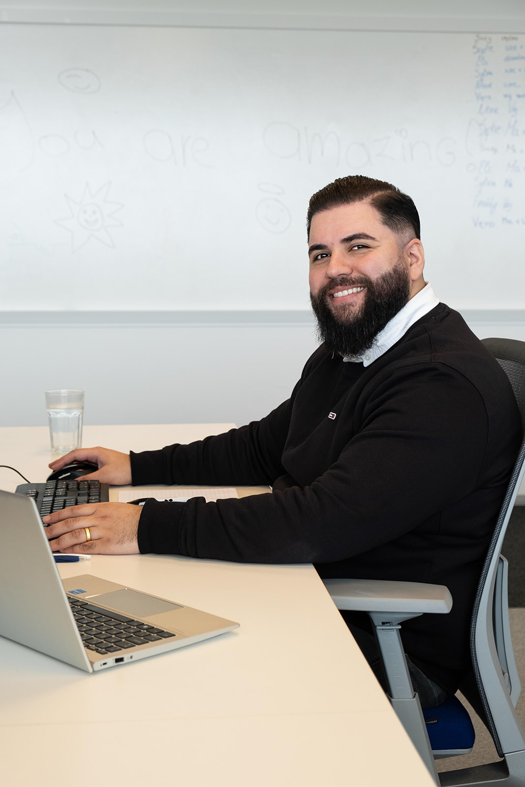 Male coworker smiling while sitting at his desk.